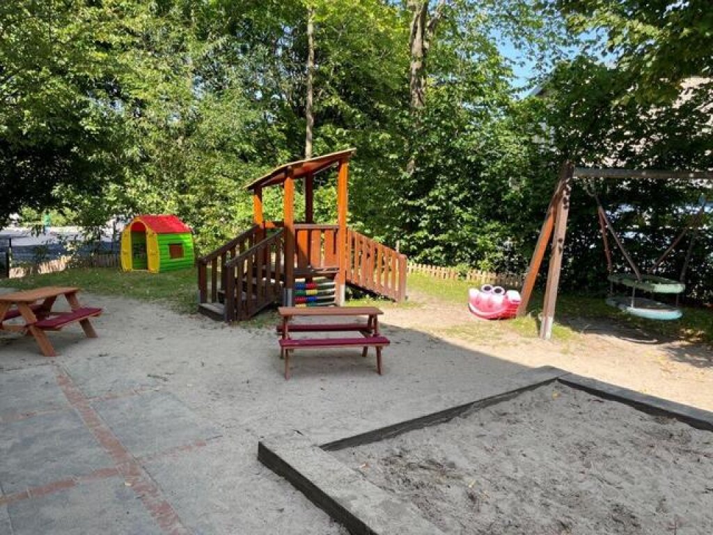 Außenbereich im Krippenbereich mit Klettergerüst und Schaukeln und Sandkasten der KIta Löwenzahn der AWO Hamburg.