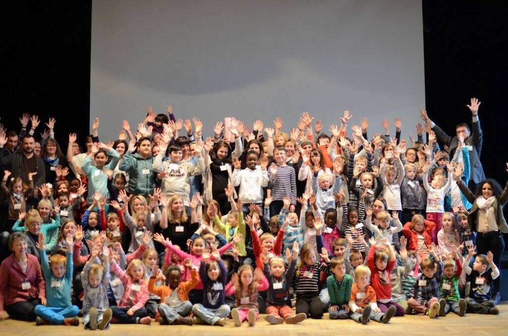 Kinder auf der Bühne heben die Hände.